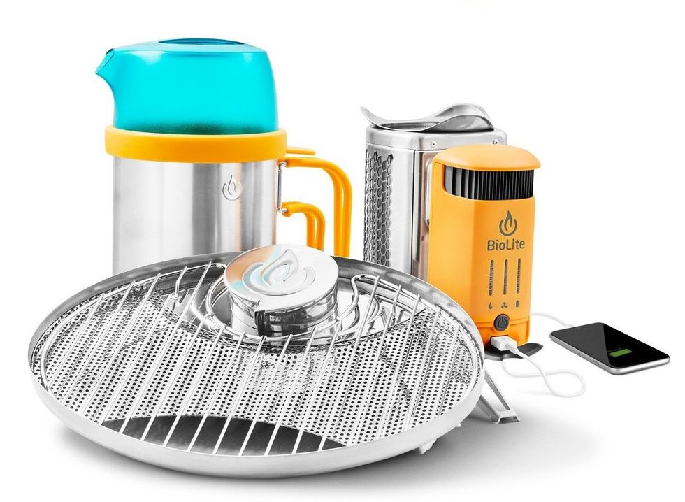 A BioLite stove next to other camping gear including a smartphone and charger