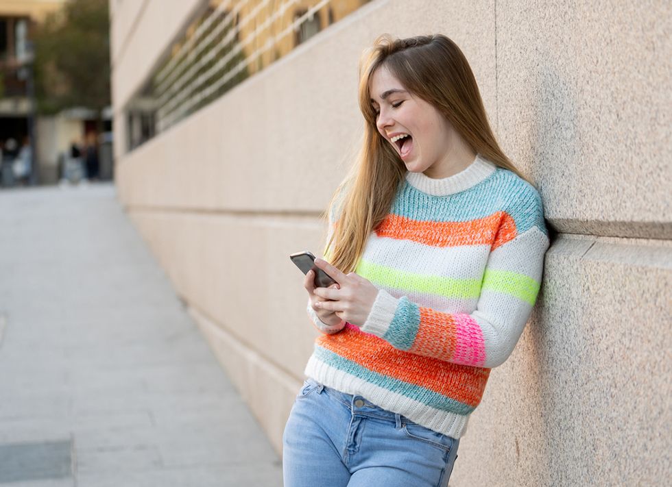 Happy young woman looking at her social media profiles on her phone.
