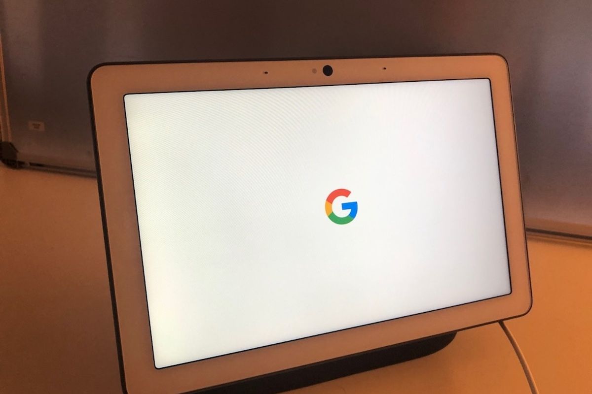 The Google Home Max with the Google logo on the screen on a white cabinet