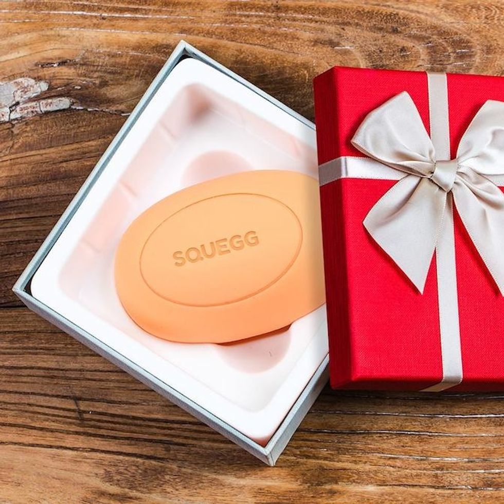 The Squegg ball inside a red box with a silver ribbon on a wood table
