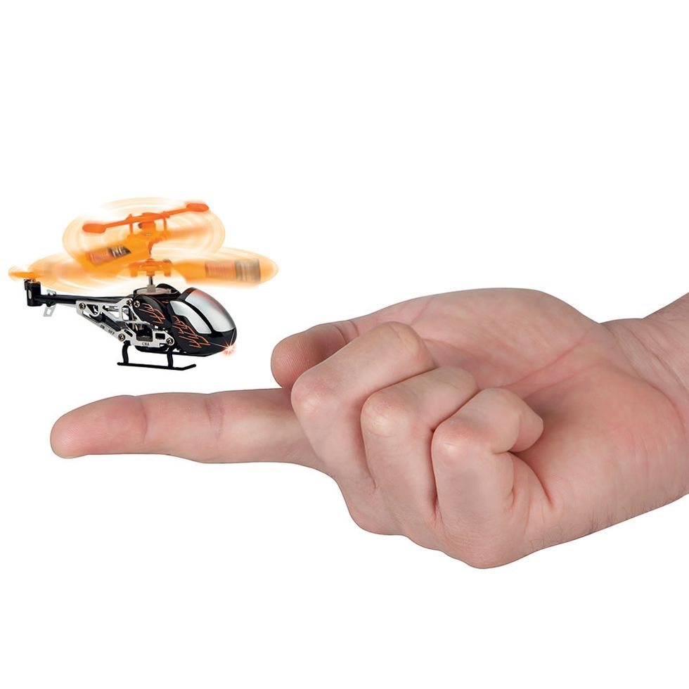 A hand with a finger our, and a tiny helicopter hovering in the air