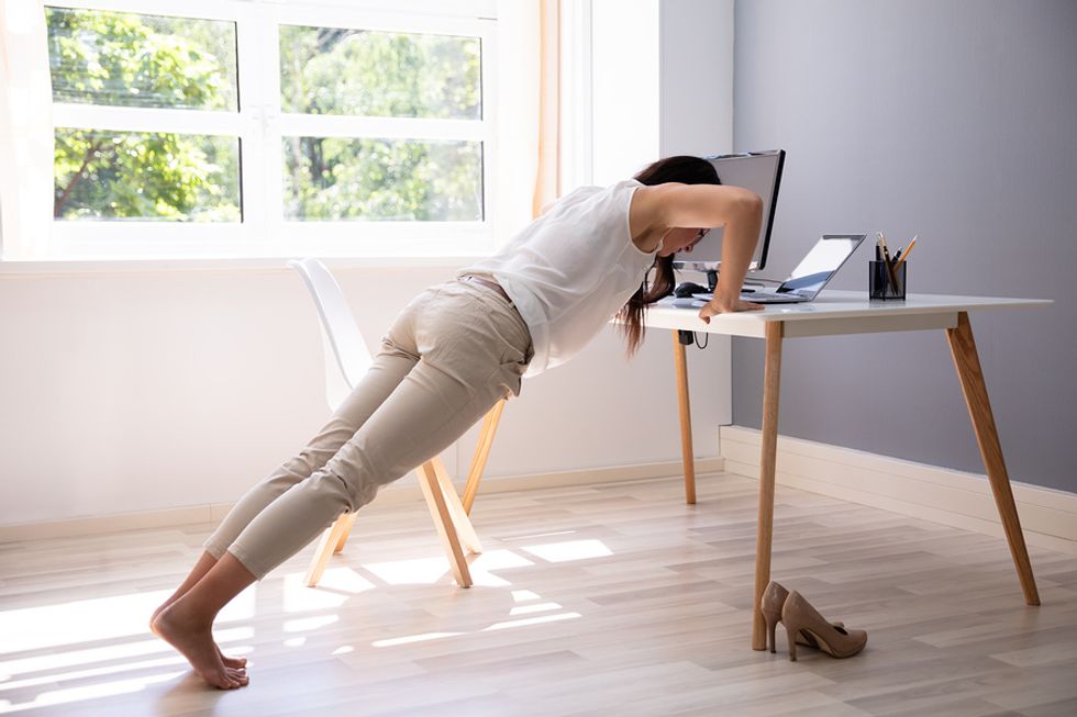 Woman doing push ups at her desk at work
