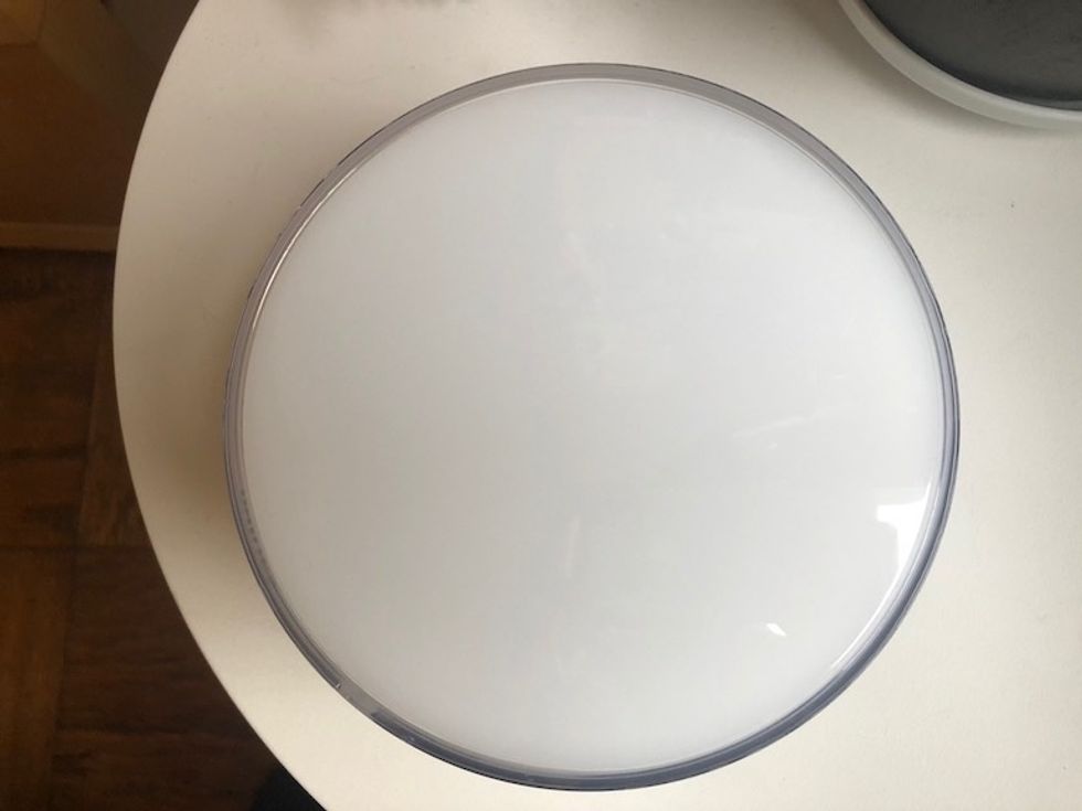 The round, white Philips Hue Go light on a white table as seen from the top