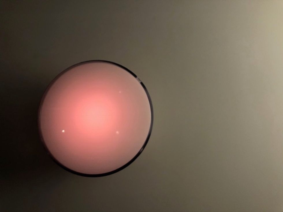 The Philips Hue Go lamp glowing  in a reddish pink color