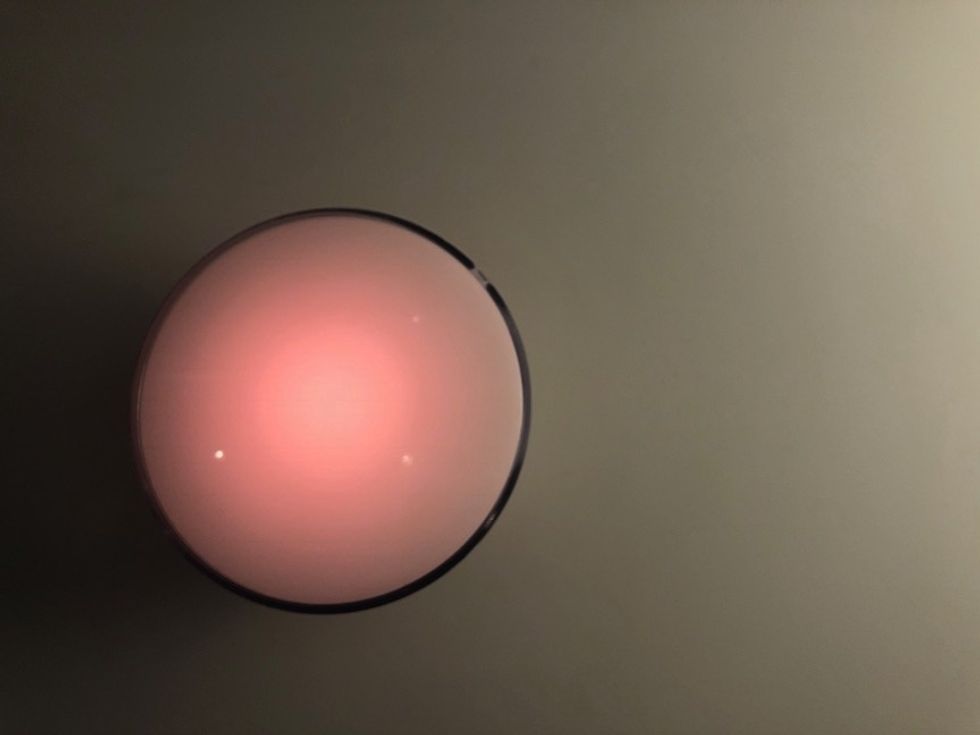 The Philips Hue Go lamp glowing  in a reddish pink color
