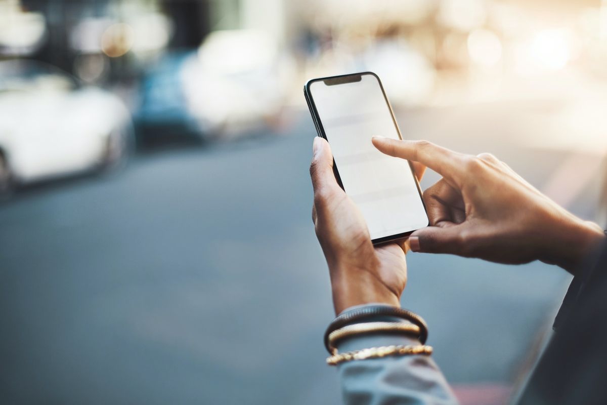 Someone holding an iPhone in their hands while standing on the street