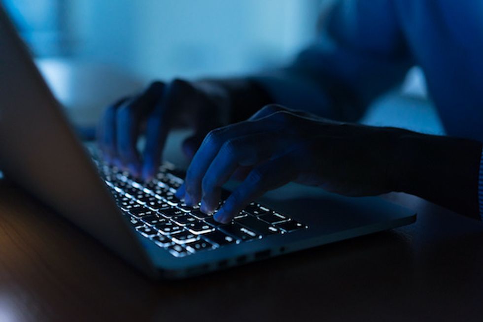 Two hands typing in the dark on a backlit keyboard