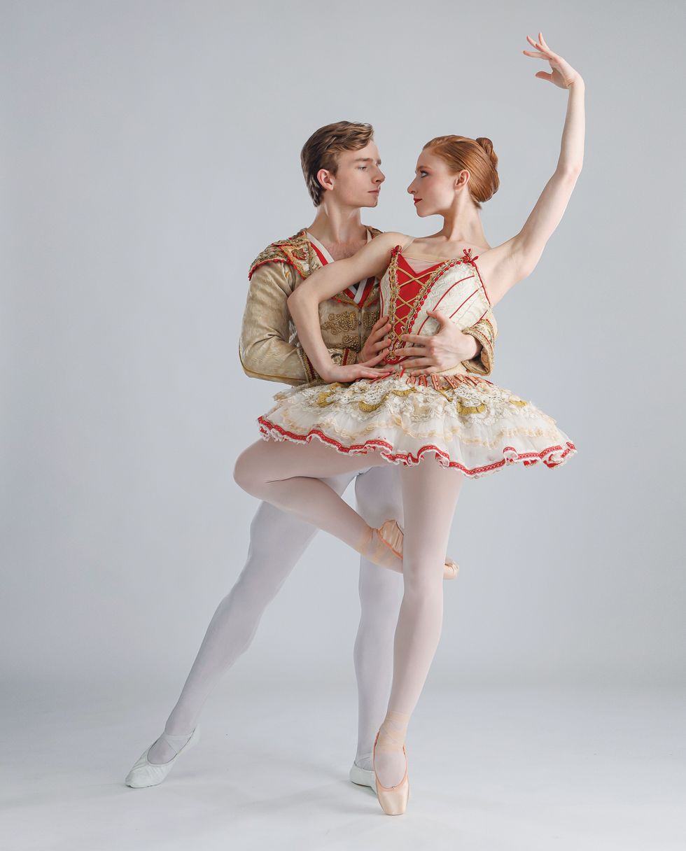 Bell and Hurlin pose against a light grey background dressed in red and gold Don Quixote costumes.