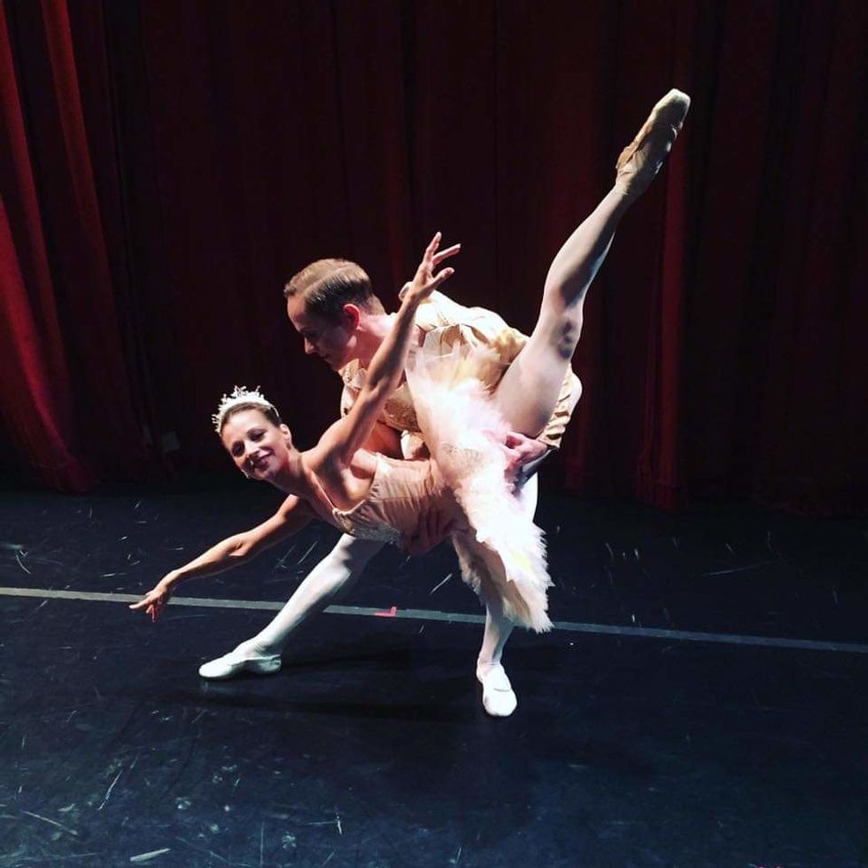 Luke Joiner lifts Jennifer Goodman, who wears a pink tutu, into a "fish" lift backstage.