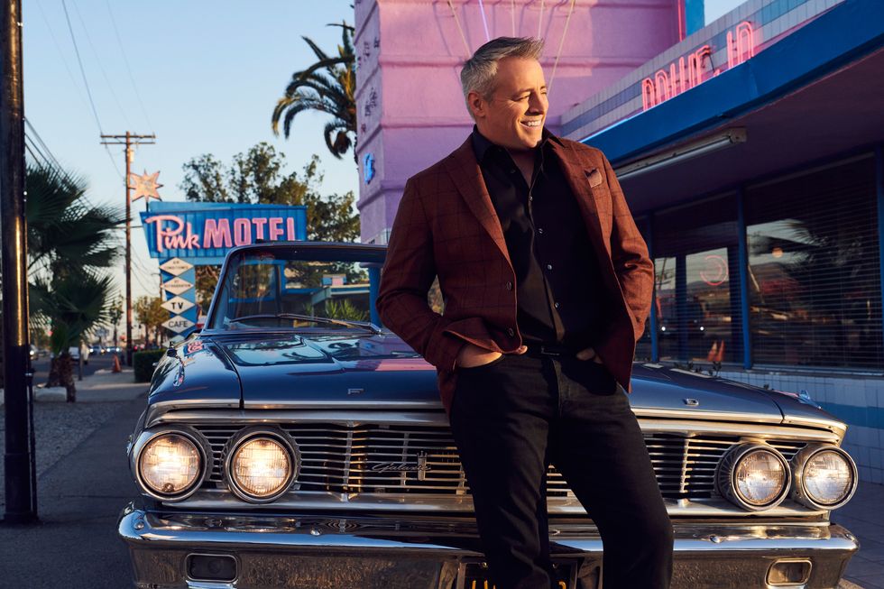 Actor Matt LeBlanc leaning against a classic Ford in front of a vintage diner.