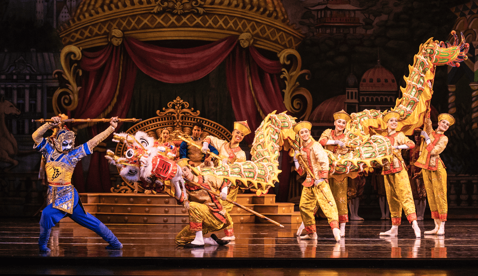 A dancer in blue leads a group carrying a Chinese dragon.