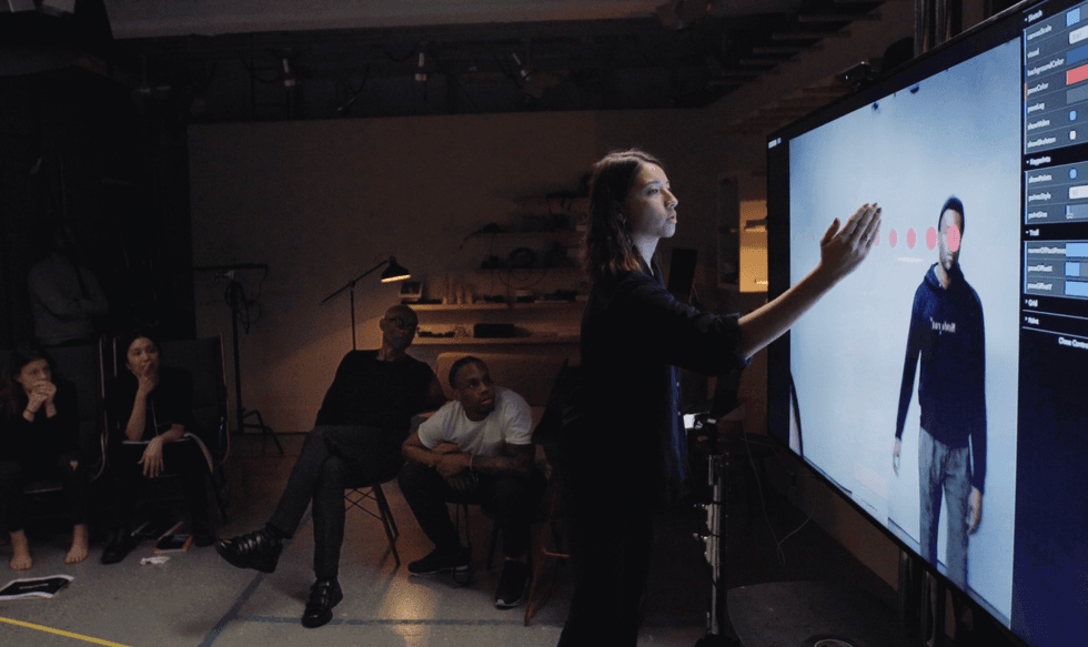 Maya Man points at a screen with a dancer on it while others look on.