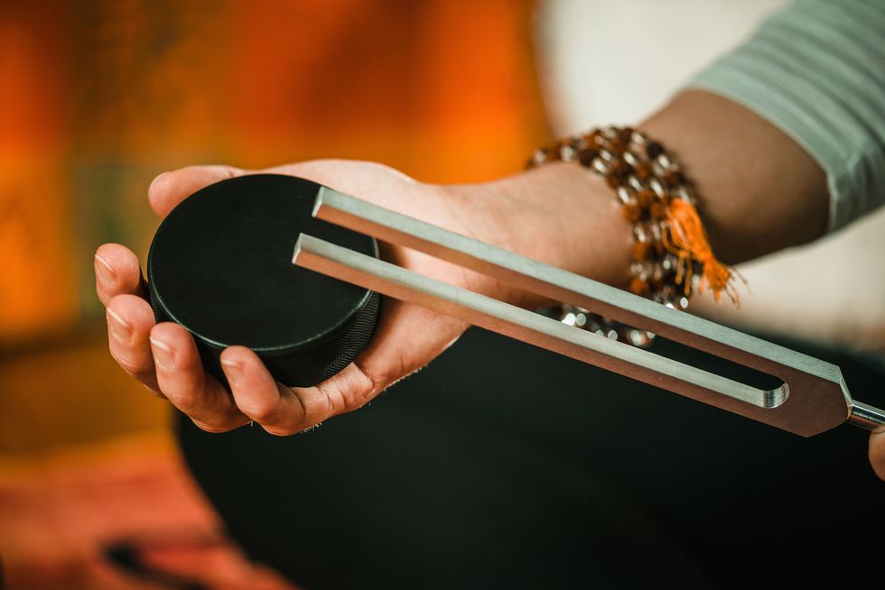 Hands holding a tuning fork and rubber puck for tuning fork therapy