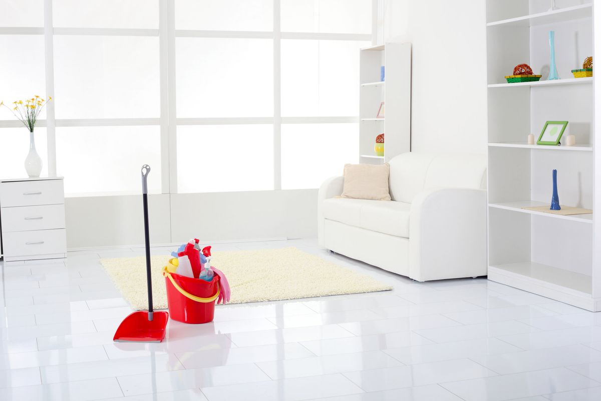 A clean white room with a red bucket of cleaning supplies