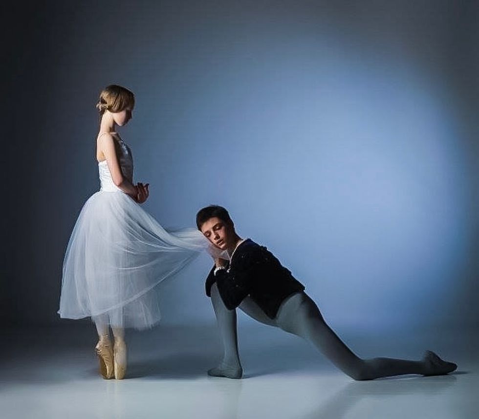 Frenette in a black jacket and grey tights kneels at Crymble's feet, holding the hem of her skirt against his cheek. She stands in a romantic tutu very upright on pointe with her hands held in the classic Giselle formation.