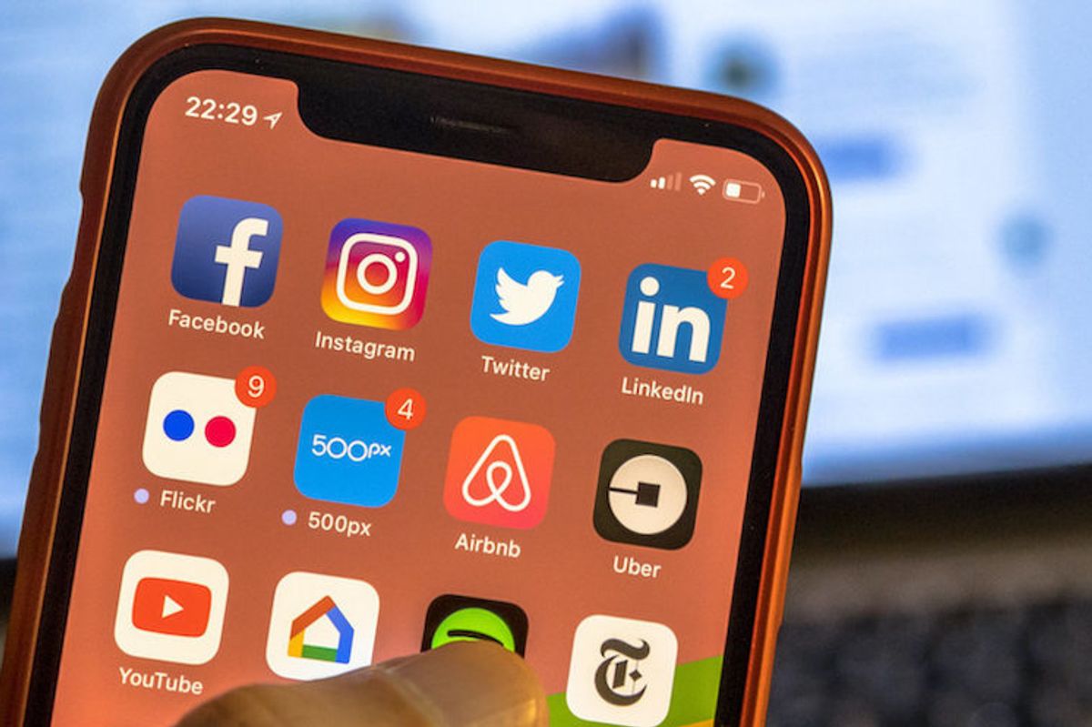 A smartphone with social media apps displayed including Twitter