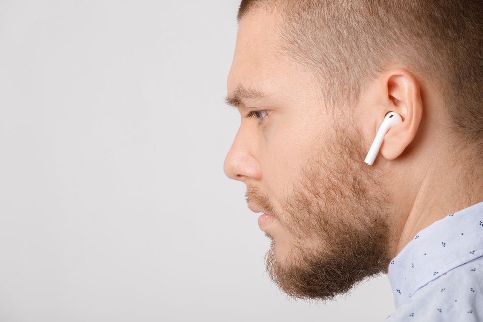 Stock image of man using Apple AirPods earphones