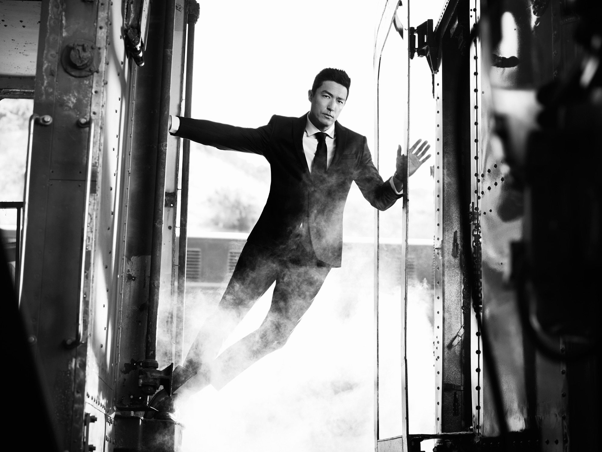 Daniel Henney leaning out the back of a vintage train car.