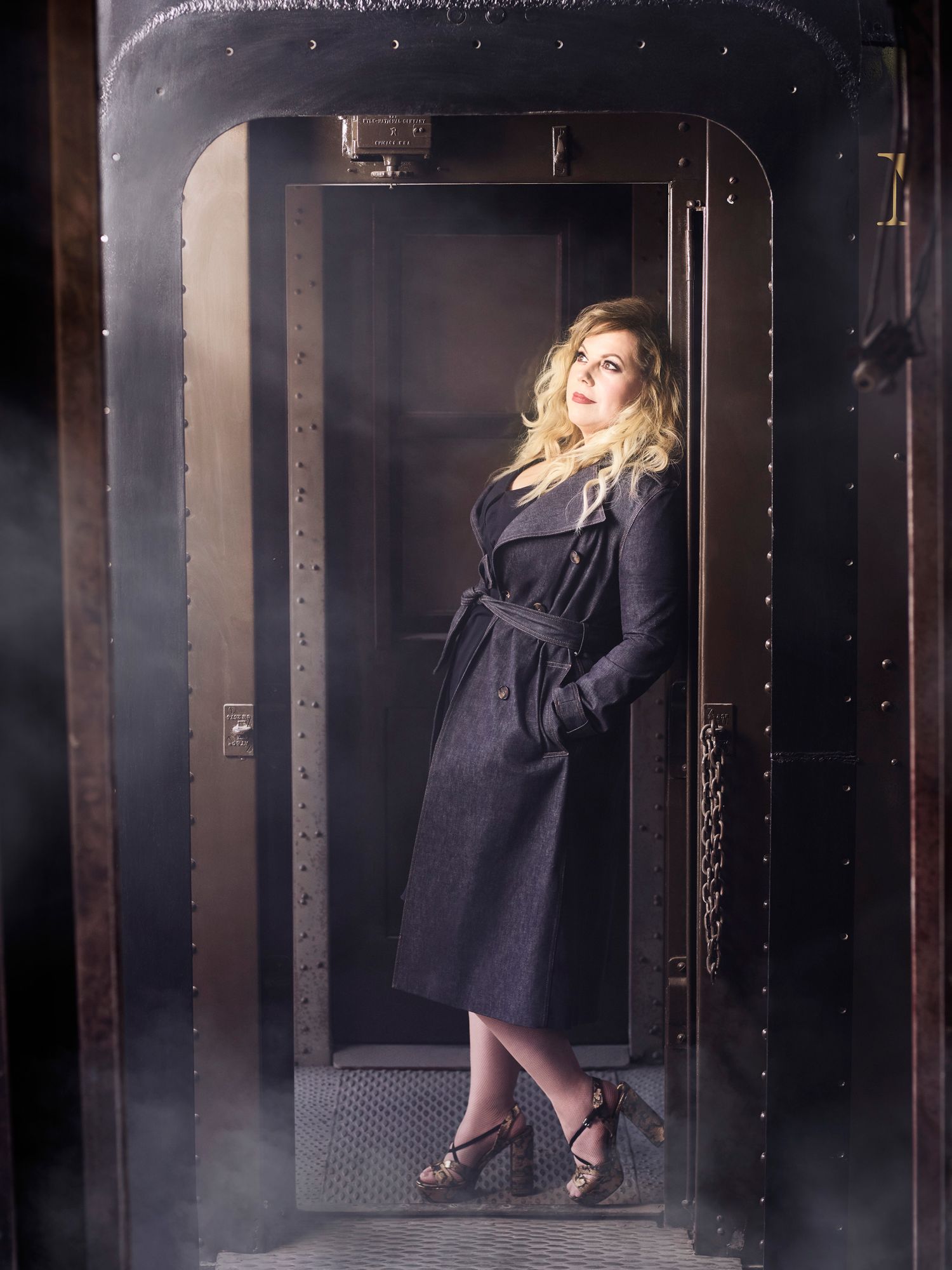 Kirsten Vangsness in black trench coat.