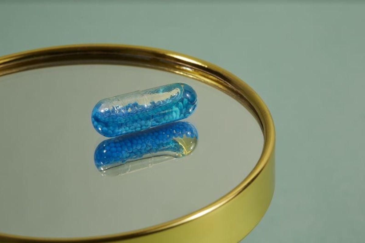blue hundred vitamin capsule on a mirror
