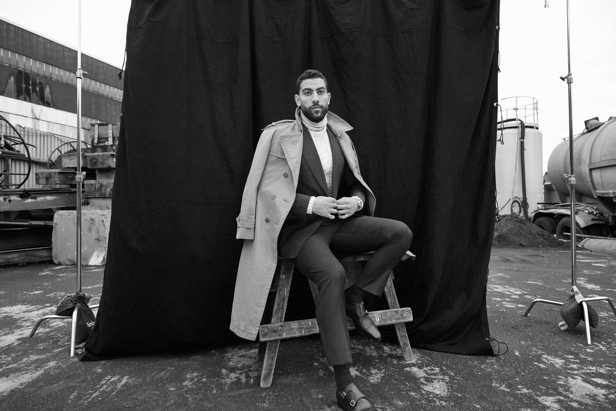 Black and white photo of Zeeko Zaki modeling a suit and trench coat.