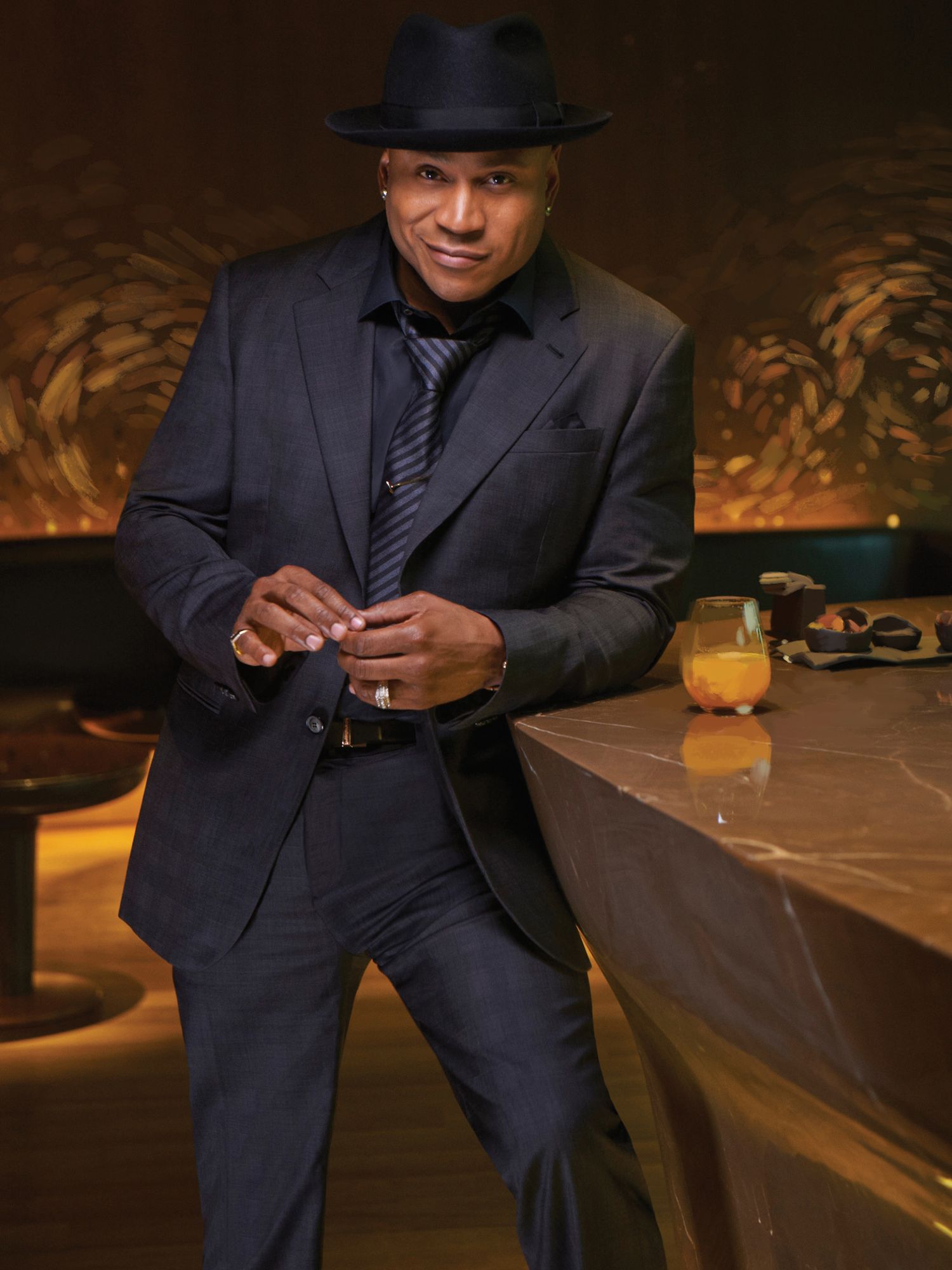 LL COOL J of NCIS Los Angeles smiling in black on black tuxedo with hat