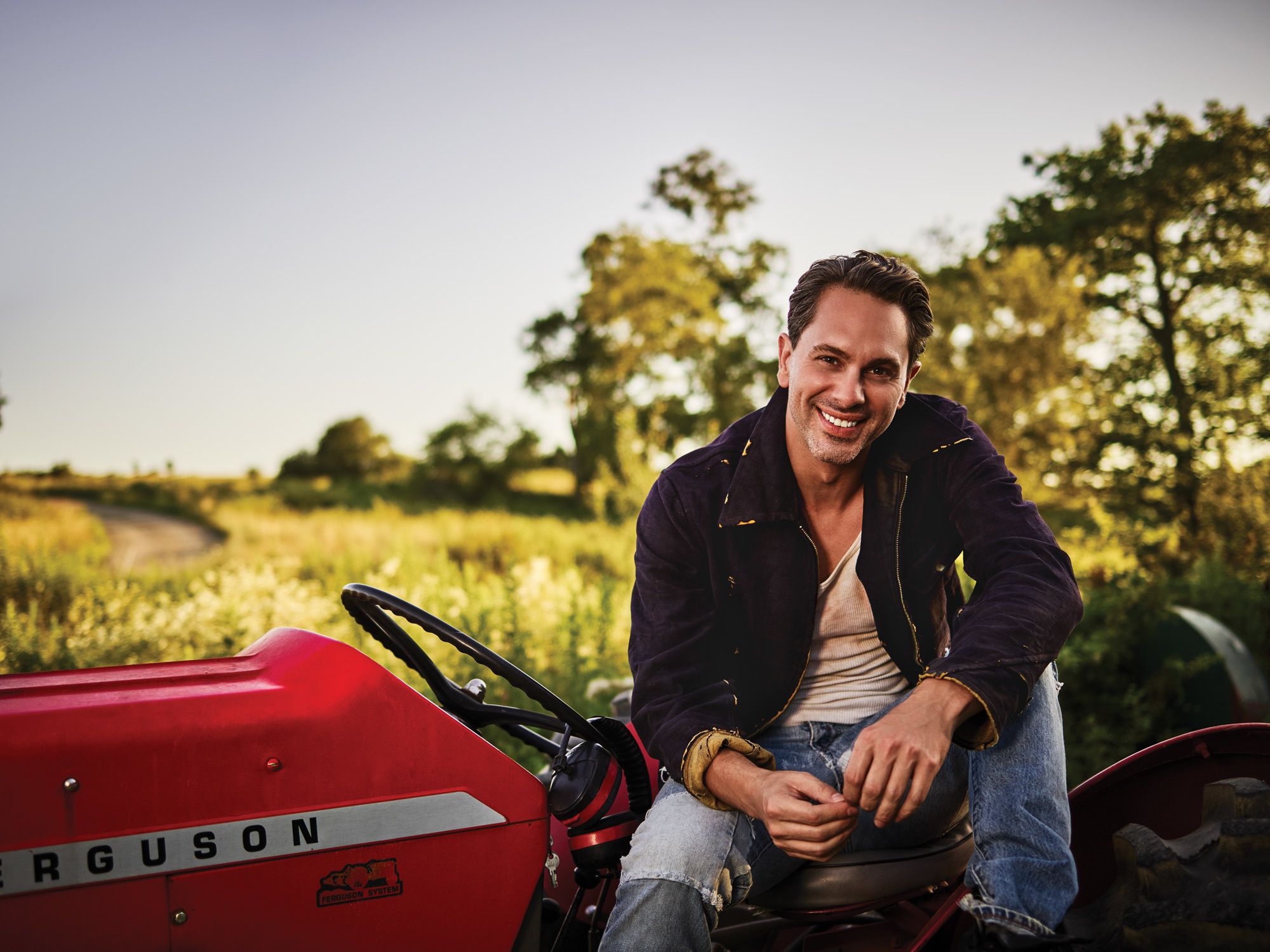 Thomas Sadoski in jeans on a tractor