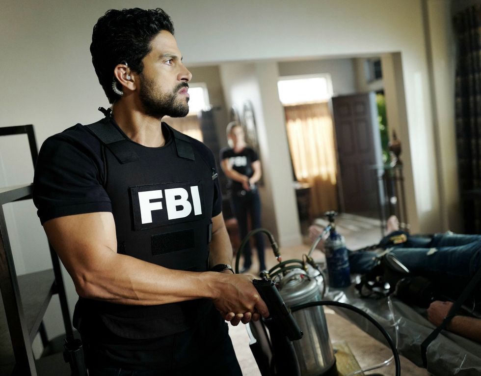 Alex Rodriquez as his character Eric Delco wearing a FBI uniform and holding a gun pointed down