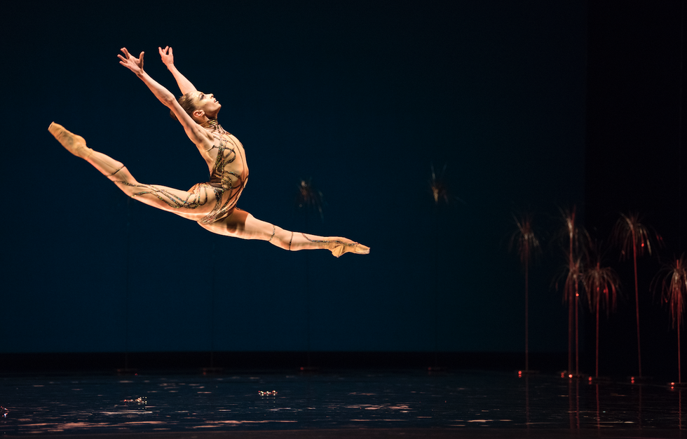 Andr\u00e9, in a gold bodysuit, leaps across the stage.
