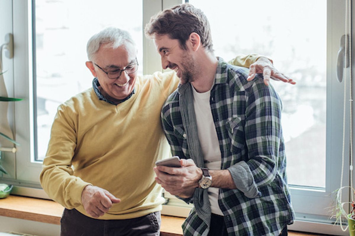  Two people looking at a smartphone and smiling near a bright window