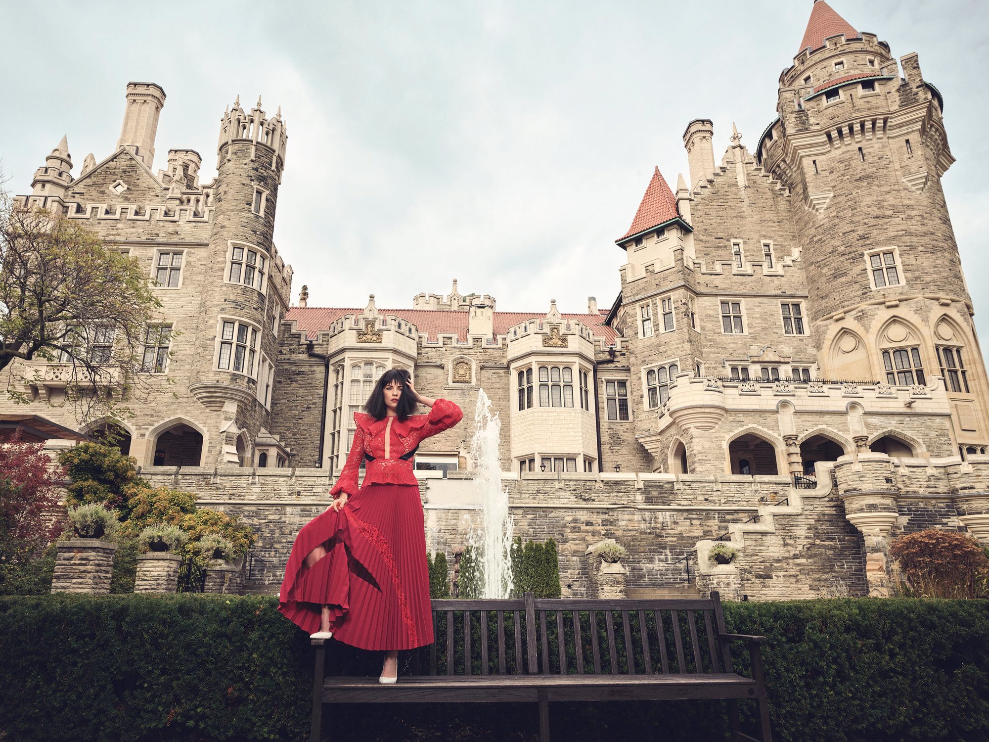 Annie Murphy in red in front of a castle.