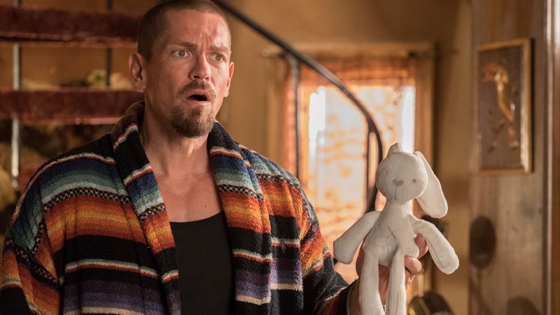 Steve Howey holding a stuffed animal bunny toy.