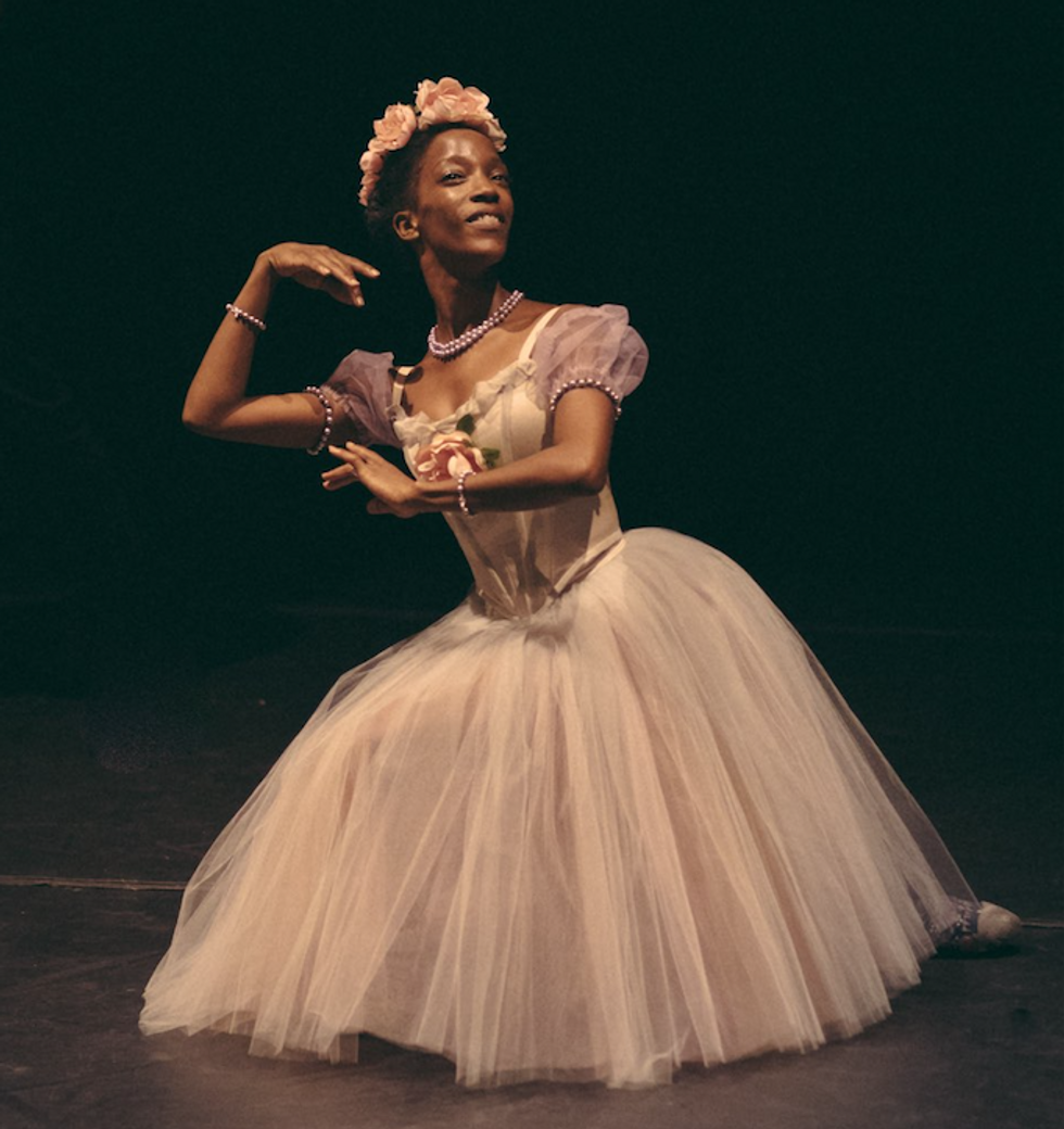 Jones, dressed in a very pale pink tutu costume, poses on the ground with her arms framing her face.