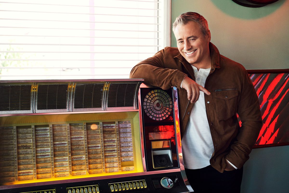 Matt LeBlanc standing at a vintage juke box wearing a brown suede jacket.