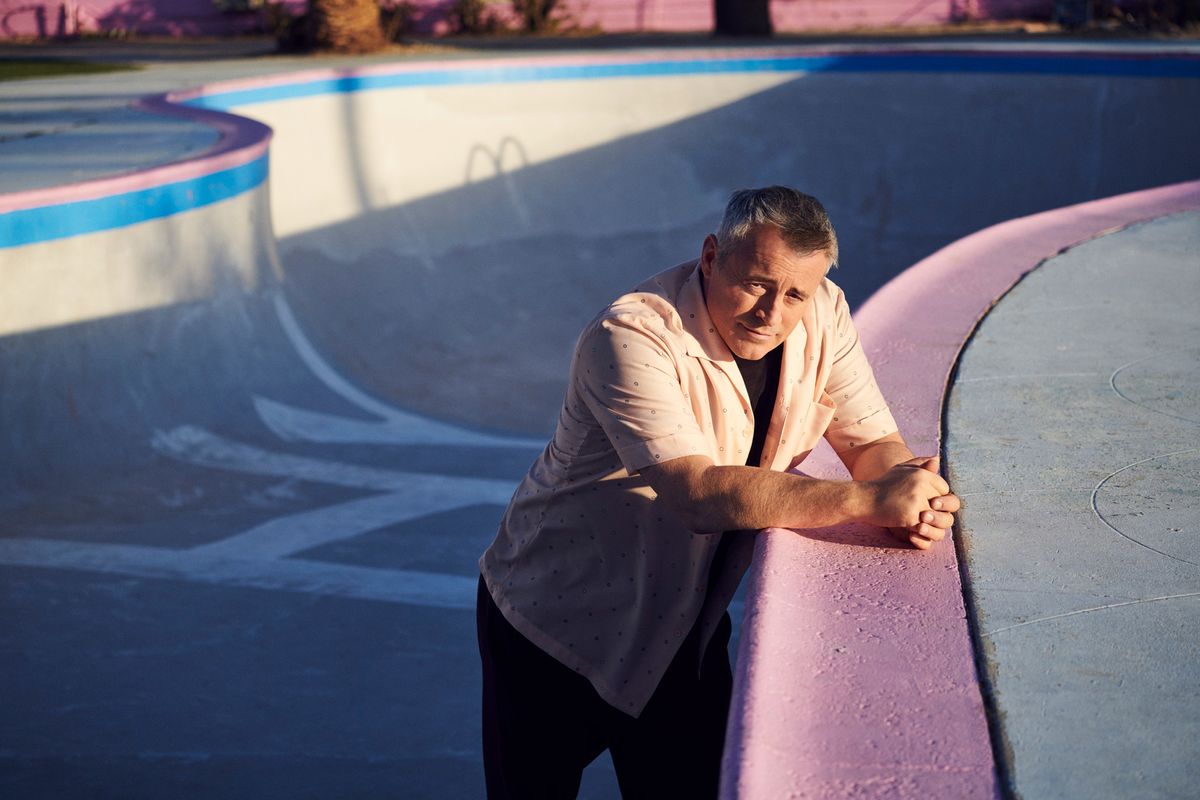Matt LeBlanc standing in an empty swimming pool wearing a vintage short-sleeve collar shirt.