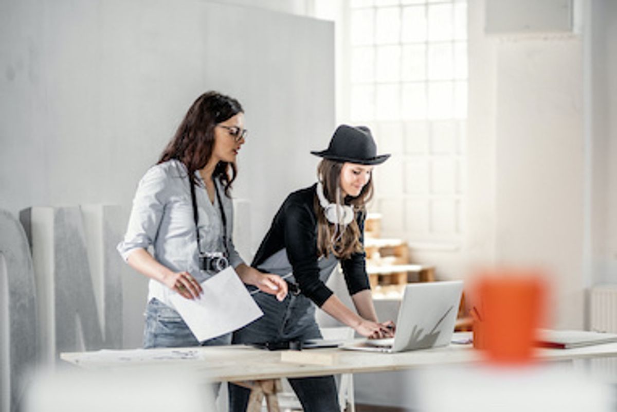 Two women working together on a creative project on their computer