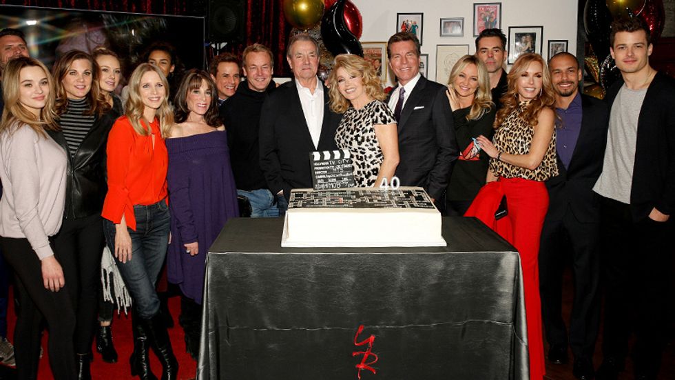 Melody Thomas Scott with a crowd of friends in family in front of her celebratory cake