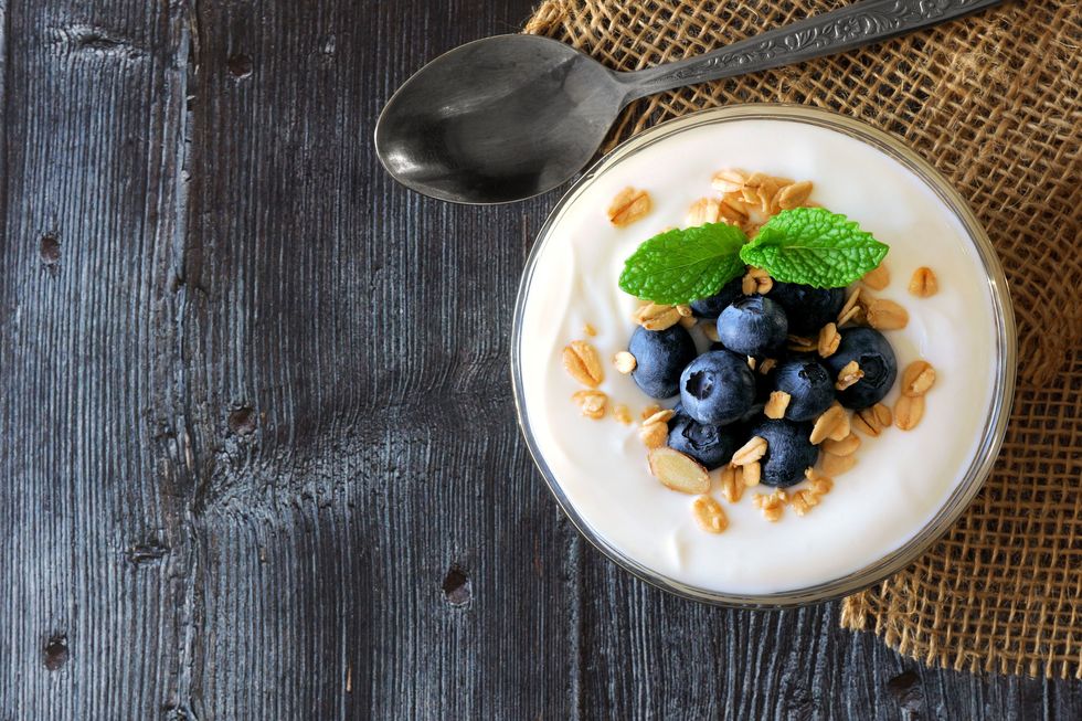 A bowl of Greek yogurt with blueberries on wood planks