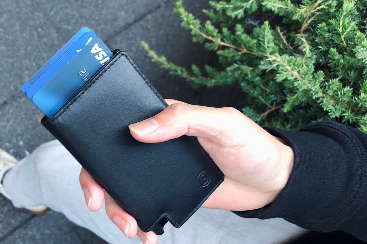 a man holding his slim black ekster wallet in his hand