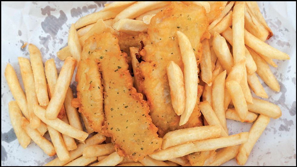A closeup image of fried fish on fried potatoes.