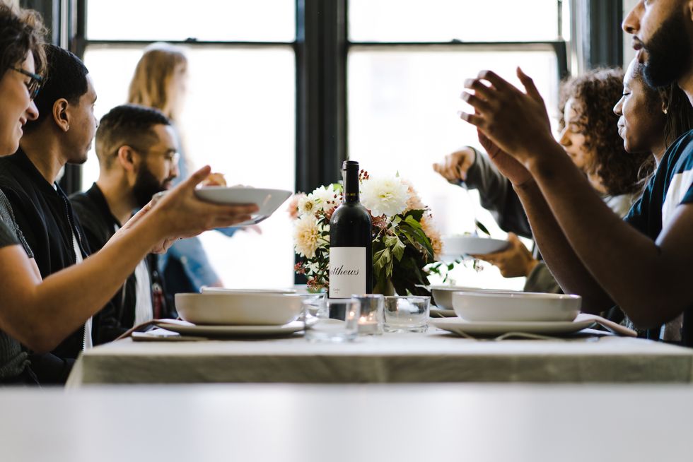 People of color at a long table having a dinner party.