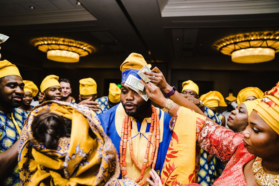 Spraying money at Nigerian weidding. Green yellow and red West African fabrics.