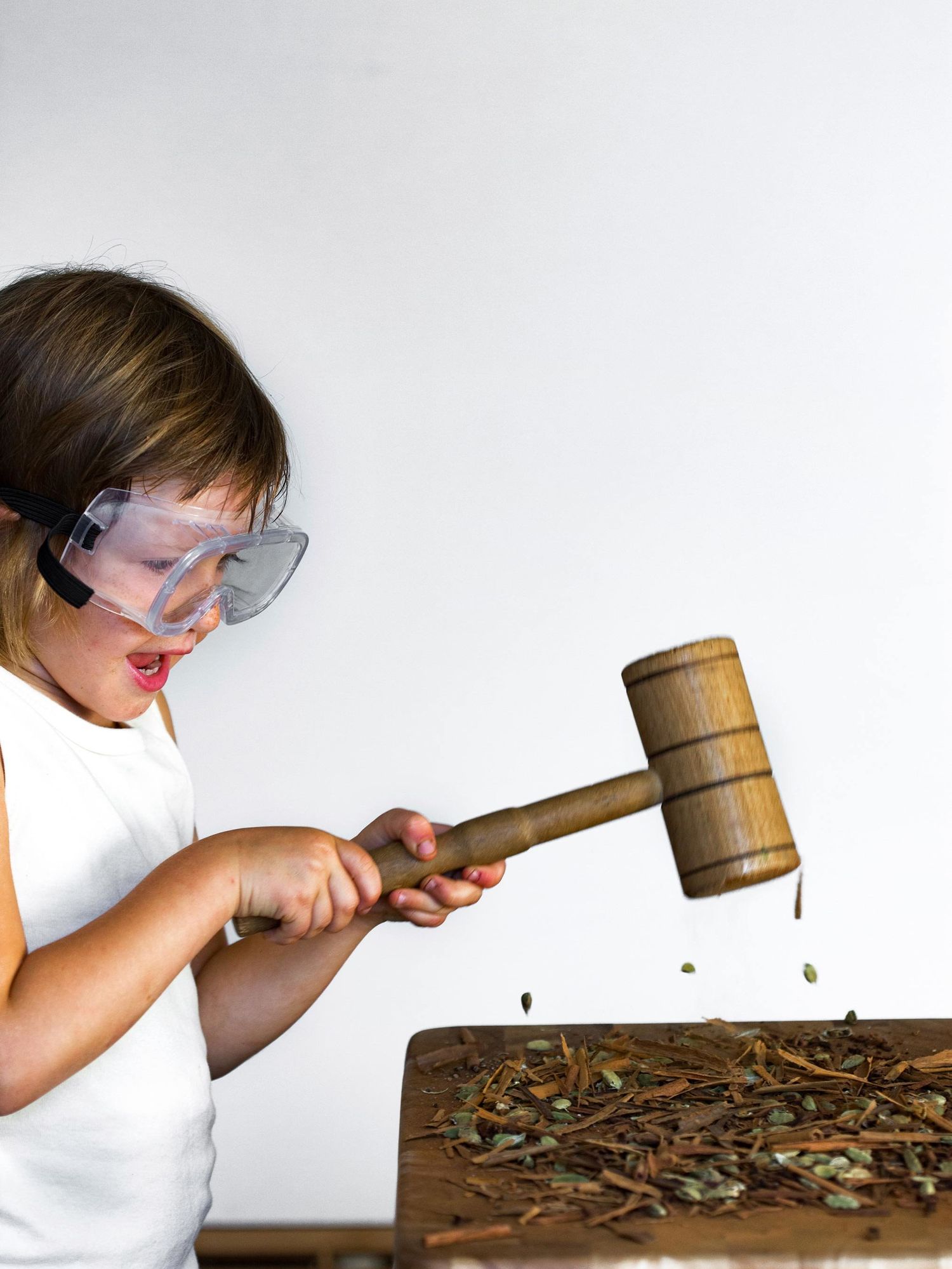 Child smashing herbs with a cooking mallet.