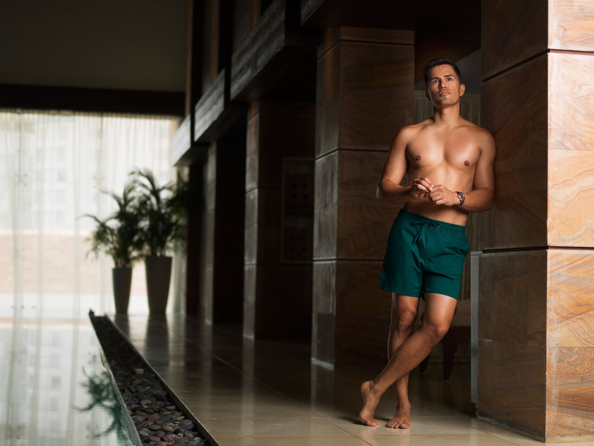 Jay Hernandez in green swim trunks by an indoor pool