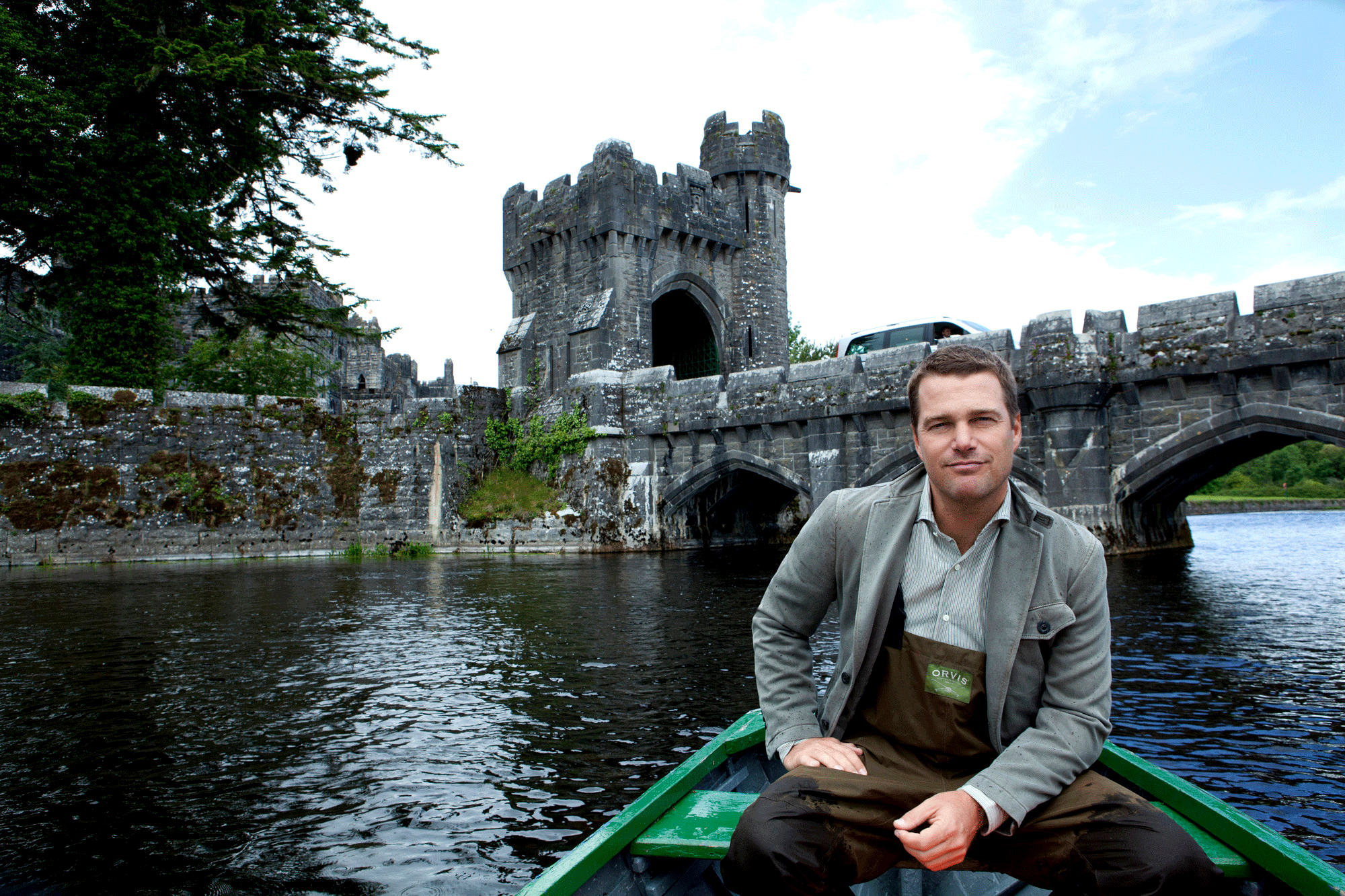 GIF image of Chris O'Donnell in row boat in a lake surrounding a medieval castle.