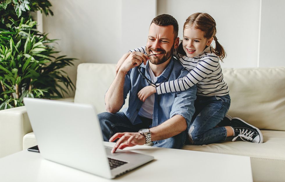 Man sits with his daughter while working from home during the COVID-19 outbreak