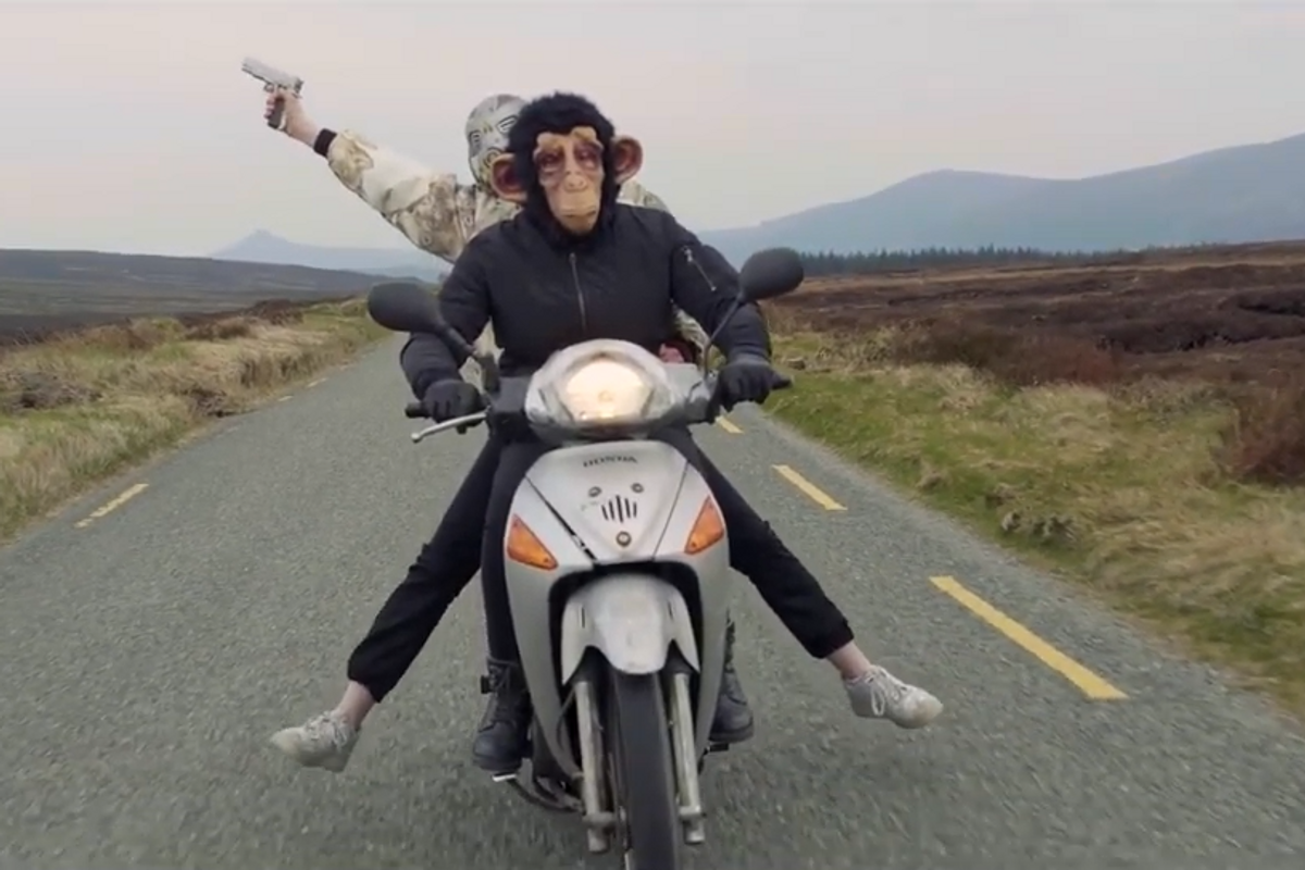 two people on a motorbike driving through fields with masks on
