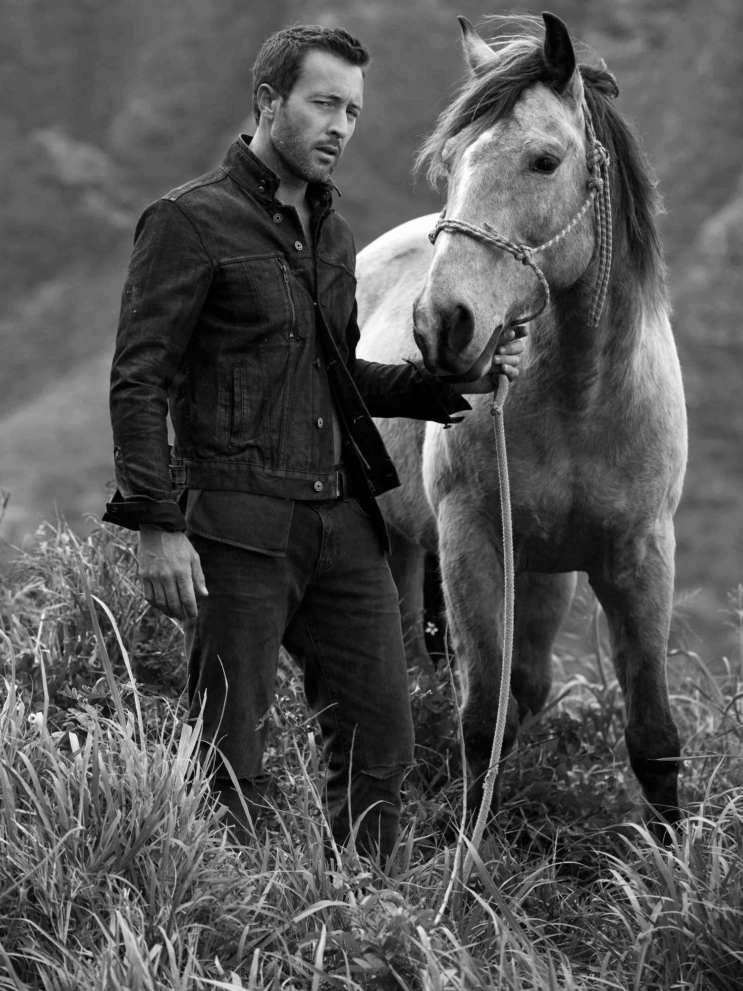 Black and white of Alex O'Loughlin posing with a horse