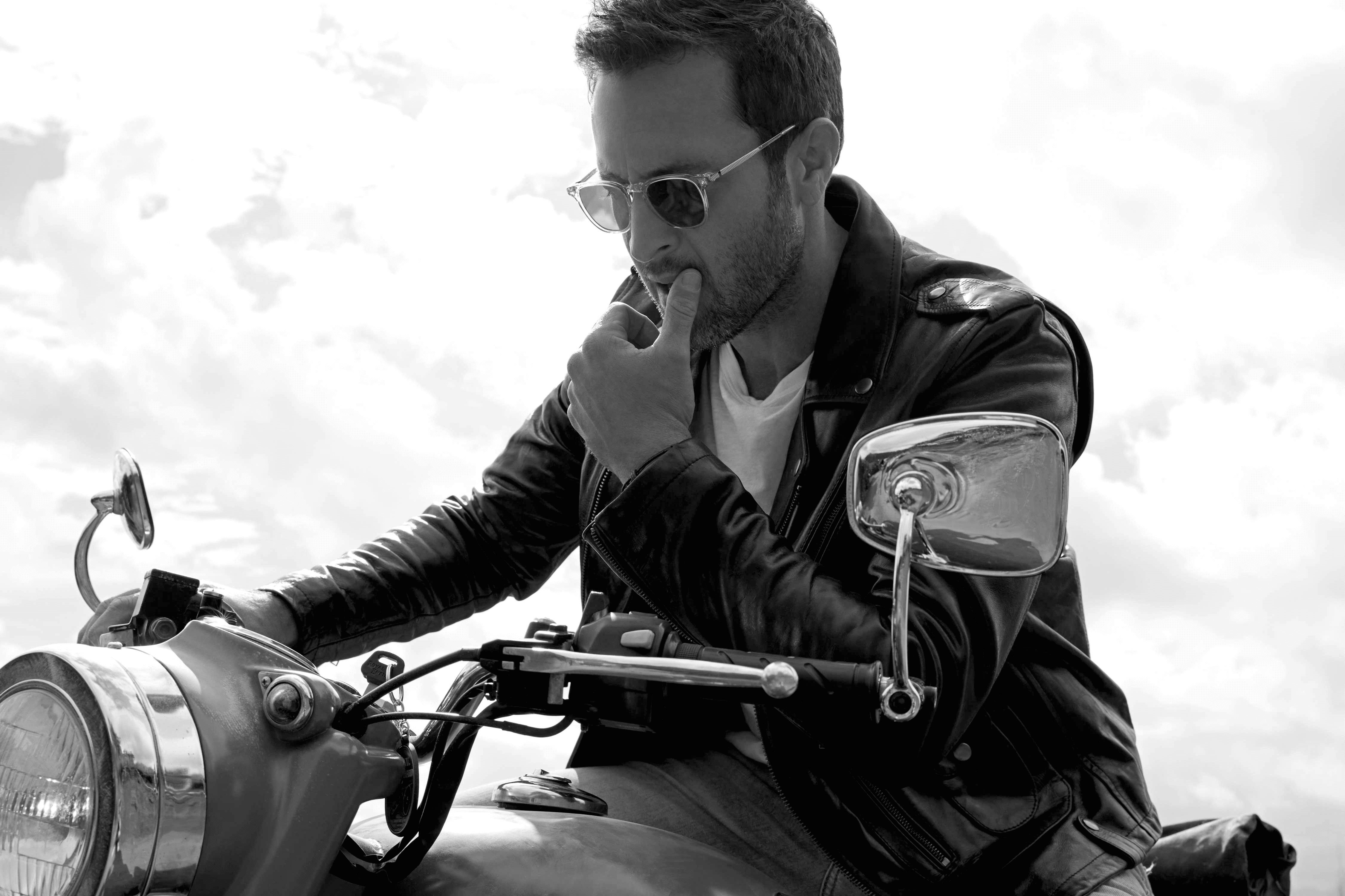 Alex O'Loughlin riding a motorcycle wearing sunglasses
