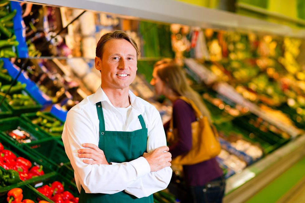 A grocery store associate stocks the produce section.